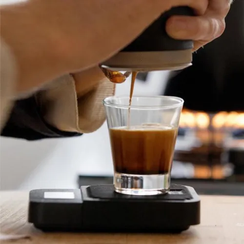 Shot of espresso on digital scales with the Picopresso held above